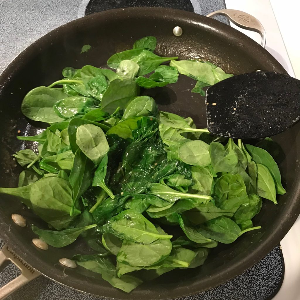 Photo of spinach being wilted in skillet